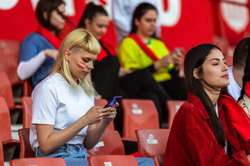 Bored sports fans using their phone at the game in the stadium. Their team is losing.