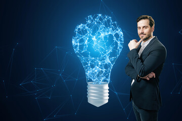 A man in a suit stands confidently next to a digital light bulb idea concept on a blue digital...