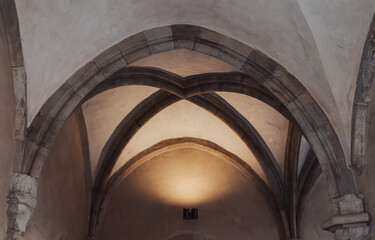 A light shines through the medieval architecture arches of a building