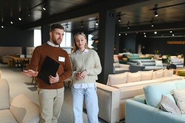 Salesman explaining to woman customer at furniture store