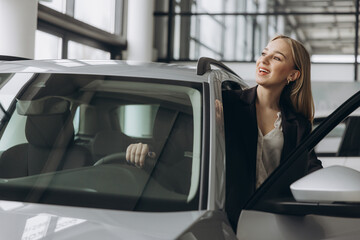 Happy amazed woman customer female buyer client wears suit open door chooses auto wants to buy new automobile in car showroom vehicle salon dealership store motor show indoor