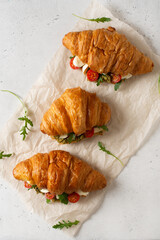 Few croissants with tomatoes, cheese and pesto with leaf arugula