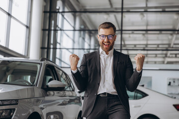 Yes, that's my new car! Customer in car dealership. Happy bearded man new car owner with keys in...