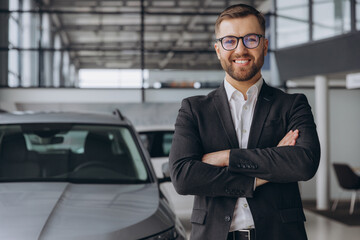Portrait of Modern car seller standing in car salon with arms crossed with copy space