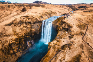 Powerful Skogafoss waterfall flowing with dry mountain in autumn at Iceland