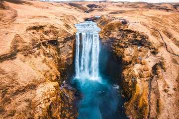 Powerful Skogafoss waterfall flowing with dry mountain in autumn at Iceland