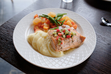 Grilled salmon steak with mashed potato and vegetables on white plate