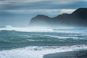Moody sea with breaking wave on coastline