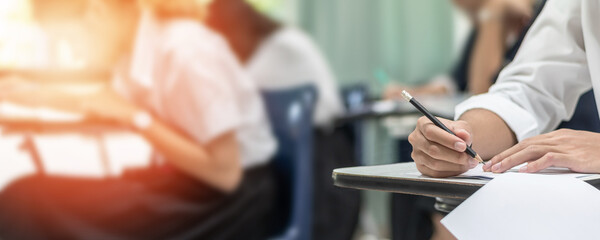 Exam at school with student's taking educational admission test in class, thinking hard, writing answer in university classroom, education and world literacy day concept