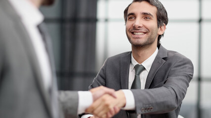 Portrait of cheerful young manager handshake with new employee.