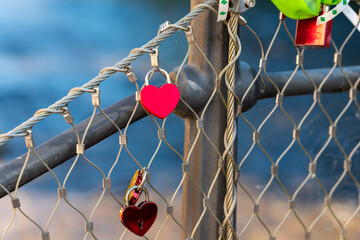 chain link fence with red heart shaped charms hanging from it