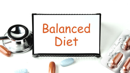 Balanced food. Balanced Diet text written on a white business card on a stand on a white background.