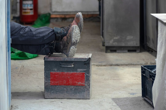 worker rests in the workshop with his feet on a box