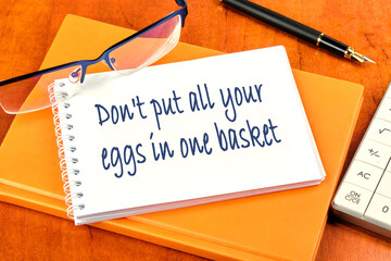 Don't put all your eggs in one basket Message inscription on the notebook lying on the notebook on...