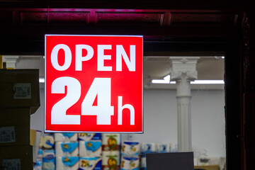 Red Open 24 hours sign outside a store window - Powered by Adobe