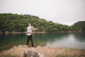 Side view of grey hair fisherman casts his line