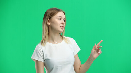 A woman, close-up, on a green background, points to the side