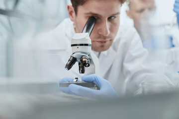 close up. the scientist looks through the microscope