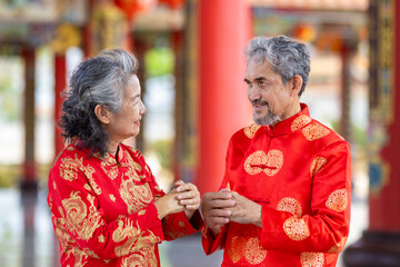 Asian marriage senior couple in cheongsam qipao dress is making a wish to ancestral god inside...