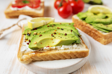 Sliced avocado on toast bread with spices on white wooden background. Food concept.