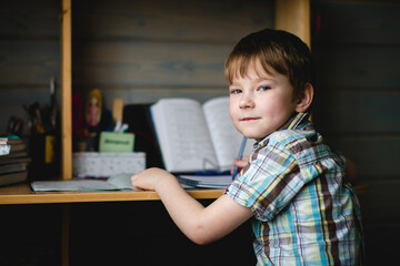 A young schoolboy does his homework, focused and diligent at his desk.