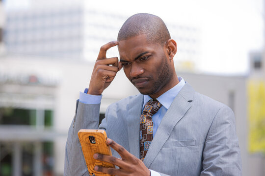 puzzled confused business man looking at his cellphone thinking what to reply to a text message on mobile phone