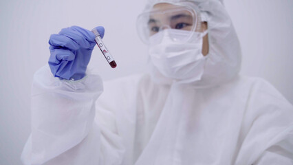 A scientist wearing protective gear examines a blood sample in a laboratory, ensuring precision and safety during the analysis process.  