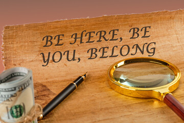 BE HERE, BE YOU, BELONG Words written on papyrus next to a magnifying glass and money