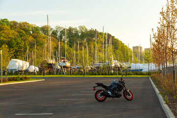 Small motorcycle in empty parking next to the Sillery marina at dawn, with boats in soft focus...