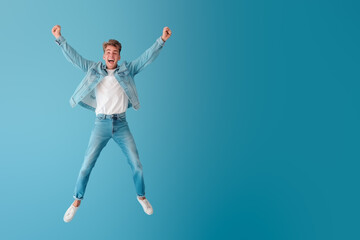 Funny young man jumping, on light blue background