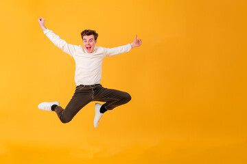 Obraz premium Funny young man jumping, on yellow background