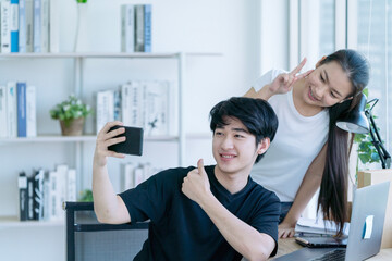 Fototapeta premium Selfie together. Boy and girl studying online. Cheerful beautiful teenager standing with mobile phone.