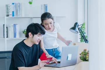 Romantic couple using laptop. Young man and smiling beautiful woman are sitting relaxed in room on open terrace and watching something on laptop