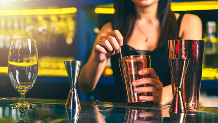 Close up of female bartender mixing an alcohol drink at the bar.