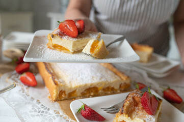 Woman serving a plate with a piece of fresh baked cheesecake with apricots