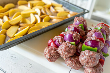 Uncooked and raw meat skewers with peppers and onions on kitchen counter