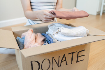 person separate clothes for donation into boxes and wait to give to volunteer charity to share to...