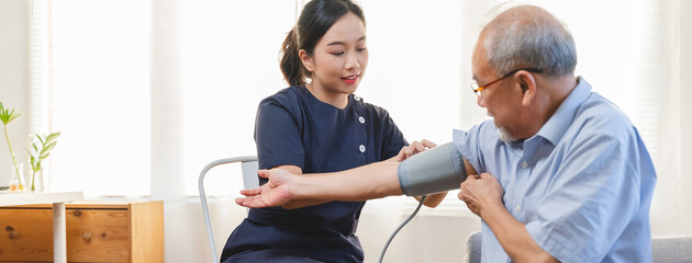 Nurse care service for retirement people, professional female caregiver measuring blood pressure senior man at home.