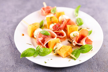 plate of melon and prosciutto ham with basil salad