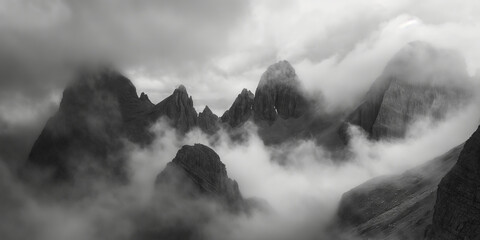 Fototapeta premium A dramatic black and white portrayal of a misty mountain range, accentuated by clouds and rugged peaks, evoking a sense of mystery and timeless natural beauty.