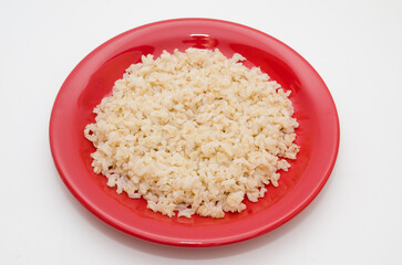 Plate of cooked brown rice on a white background