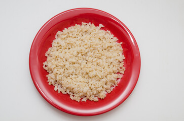 Plate of cooked brown rice on a white background