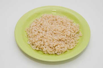 Plate of cooked brown rice on a white background