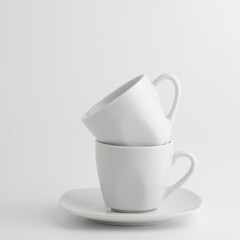 Photo of two white cups stacked on top of each other against a white background, creating a minimalist and conceptual all-white tone composition