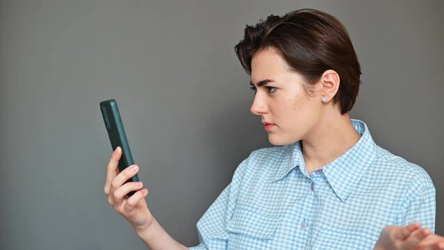 An unpleasant telephone conversation, an irritated young woman using a video call on a smartphone and swearing at her interlocutor