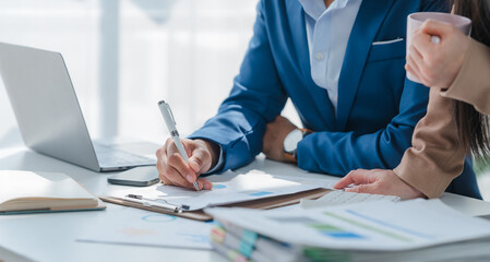 Asian business team discussing over laptop in a corporate. Group collaboration and teamwork concept.