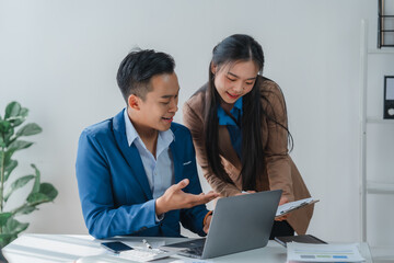 Obraz premium Asian business team discussing over laptop in a corporate. Group collaboration and teamwork concept.