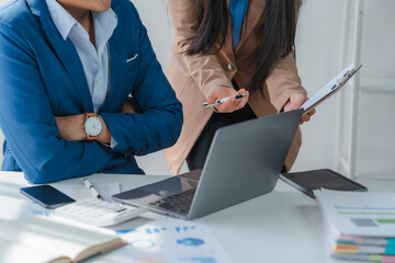 Asian business team discussing over laptop in a corporate. Group collaboration and teamwork concept.