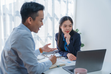 Asian business team discussing over laptop in a corporate. Group collaboration and teamwork concept.