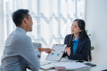 Asian business team discussing over laptop in a corporate. Group collaboration and teamwork concept.